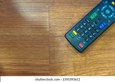 Image of remote control isolated from top right hand corner on wooden table. Focus on remote control only. 