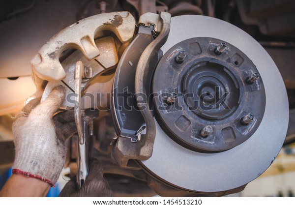 Image of replacing a new brake pad, held by a car\
mechanic who is about to change the new brake pads, cars in the car\
center