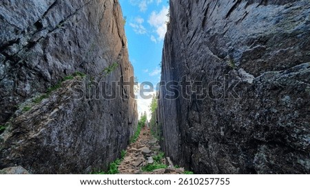 An image of a road in between of two rocky mountains under the blue sky.