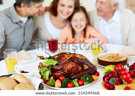 Image of roasted turkey on holiday table and family on background
