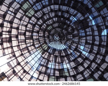image of a round, patterned glass house roof against a blue sky background