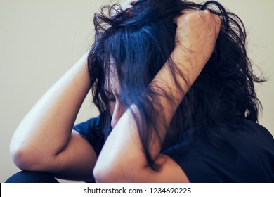Image of sad depressed 40s Asian or Japanese woman sitting on floor,her hands closed on face or pulling her untidy hair.She may be crying or pain or get mental illness or life problem.