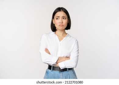 Image of sad office girl, asian woman sulking and frowning disappointed, standing upset and distressed against white background - Shutterstock ID 2122701080