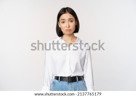 Image of sad office girl, asian woman sulking and frowning disappointed, standing upset and distressed against white background