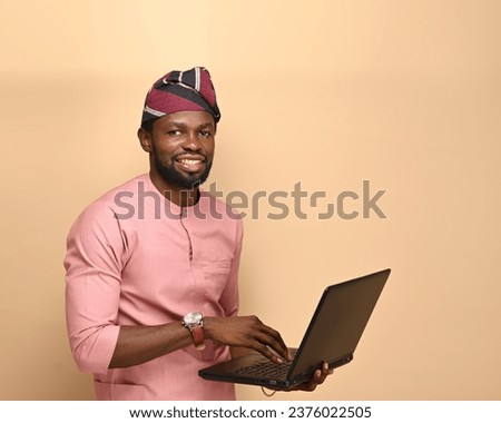 Image of a satisfied handsome man using a laptop looking away from his screen, satisfactory approval, website designer or internet IT staff, standing over brown background.