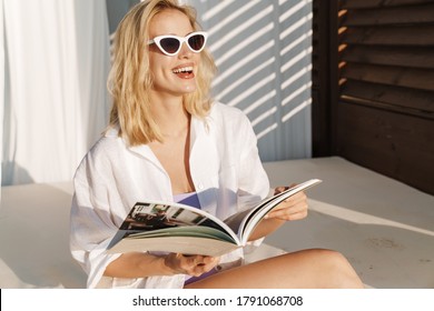 Image Of Seductive Smiling Woman In Sunglasses Reading Magazine At Hotel On Summer Beach