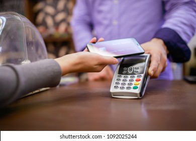 Image of seller with terminal and buyer with smartphone - Shutterstock ID 1092025244