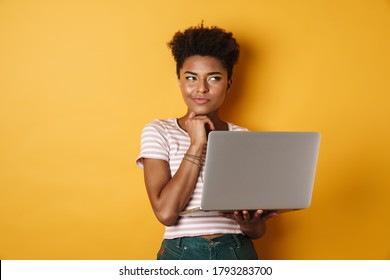 Image of serious african american woman thinking and using laptop isolated yellow background - Powered by Shutterstock