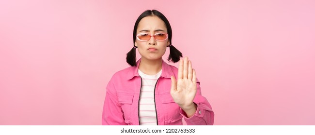 Image Of Serious, Stylish Asian Girl In Sunglasses, Showing Stop, Prohibit Gesture, Taboo Sign, Saying No, Standing Over Pink Background