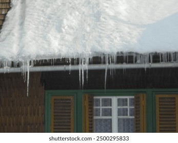 Image of Sharp icicles hanging from snow-covered roof of traditional wooden village house with slight blur. - Powered by Shutterstock