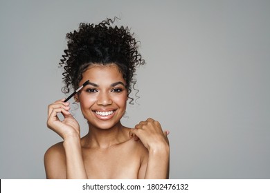 Image Of Shirtless African American Woman Using Eyebrows Brush And Smiling Isolated Over Grey Background