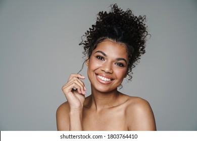 Image of shirtless african american woman looking and smiling at camera isolated over grey wall