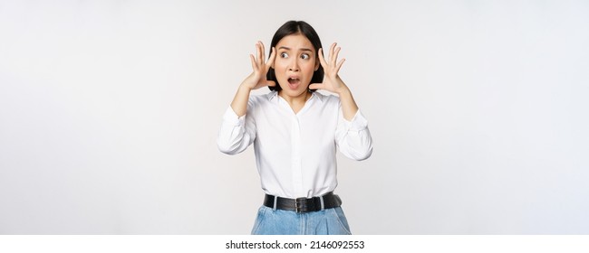 Image of shocked anxious asian woman in panic, holding hands on head and worrying, standing frustrated and scared against white background - Shutterstock ID 2146092553