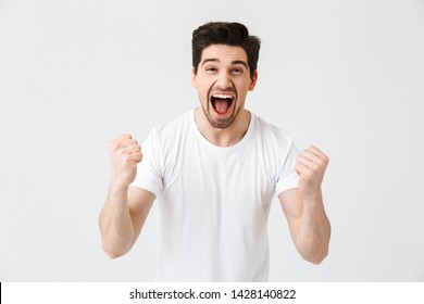 Image of a shocked surprised excited happy young man posing isolated over white wall background make winner gesture.