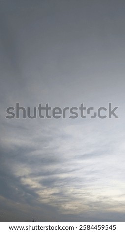 The image showcases a dramatic sky blanketed by a thick layer of dark, swirling clouds. Hints of a vibrant sunrise peek through, casting a warm glow on the lower horizon.