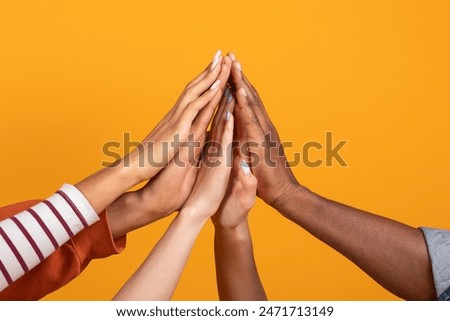 The image showcases multiple hands of various skin tones reaching upwards and touching in a gesture of unity and collaboration, cropped