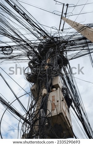 Image showcasing a considerable multitude of intertwined electric cables, representing the disorderly urban electrical networks prevalent in Asia.