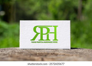 The image shows a business card featuring the logo "RPH" in bold green letters. Below it, the text reads "RAYAN PAINTS and HARDWARE STORE," set against a blurred green background.