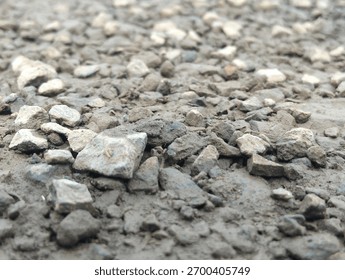 The image shows a close-up, low-angle view of a surface covered in a mixture of crushed stone and dirt. The material appears to be a type of sub-base aggregate, such as MOT Type 1 or Item 4 gravel, 