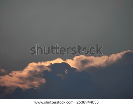  The image shows a dramatic sky with billowing, fluffy white clouds and a hint of the sun peeking through, creating a beautifully lit scene.