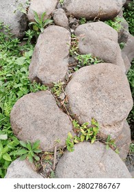 The image shows a group of large, rounded river stones or boulders arranged closely together, possibly forming a natural path, a retaining wall, or a garden border.
