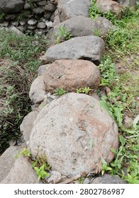 The image shows a group of large, rounded river stones or boulders arranged closely together, possibly forming a natural path, a retaining wall, or a garden border.
