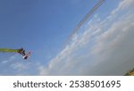 The image shows a long dragon kite soaring high in a clear blue sky. The kite has a vibrant, detailed dragon head at the front, with green segments following it, creating a lengthy, flowing tail