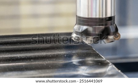 The image shows a machine tool precisely cutting or engraving a steel surface. The focus is on the interaction between the tool and the material, highlighting the precision of CNC machining.