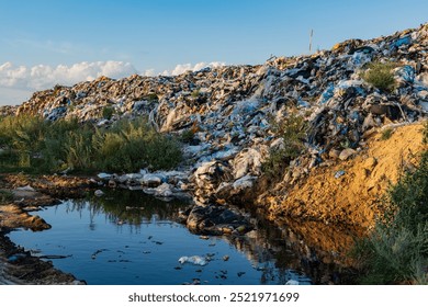 The image shows a massive pile of garbage next to a polluted pond, reflecting the urgent environmental issues caused by waste accumulation