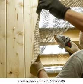 The image shows a person using an angle grinder to cut or shape a piece of expanded metal mesh near a wooden structure.