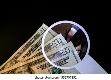 Image Shows The Use Of A Magnifying Glass To Check Whether Some 20-dollar US Bills Are Counterfeit. The Use And Production Of Counterfeit Money Is Considered A Form Of Fraud Or Forgery.