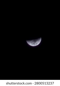 The image shows a view of a half moon at night against a completely black sky.