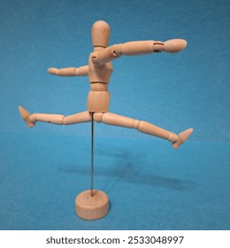 The image shows a wooden artist's mannequin in a walking pose. The figure has movable joints that allow for adjusting its posture, and it is standing on a small circular base supported by a metal rod. - Powered by Shutterstock