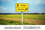 An image with a signpost pointing in two different directions in German. One direction points to I can, the other points to resignation.