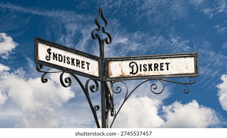 An image with a signpost pointing in two different directions in German. One direction points to Discreet, the other points to Indiscreet.