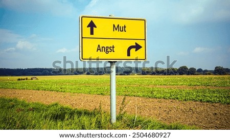 An image with a signpost pointing in two different directions in German. One direction points to courage, the other points to fear.