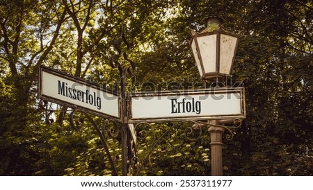 An image with a signpost pointing in two different directions in German. One direction points to success, the other points to failure.