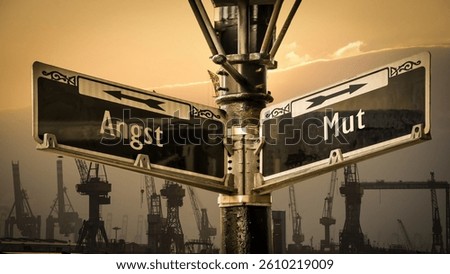An image with a signpost pointing in two different directions in German. One direction points to courage, the other points to fear.