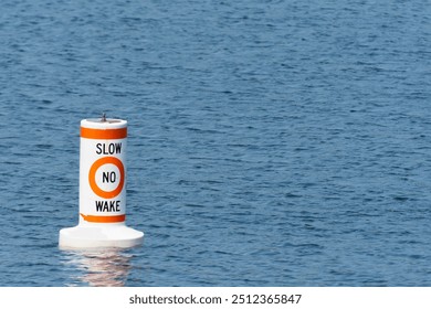 An image of a single red and white warning buoy near a designated lake side swimming area. 