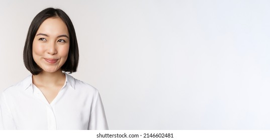 Image Of Smiling Asian Woman Planning, Thinking Of Smth, Daydreaming, Standing Over White Background With Smug Face