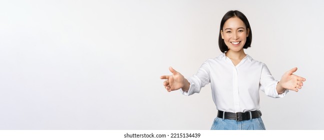 Image Of Smiling Asian Woman Welcoming Guests Clients, Businesswoman Stretching Out Open Hands, Greeting, Standing Over White Background.