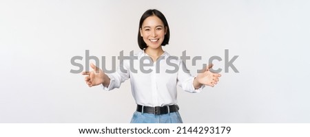 Image of smiling asian woman welcoming guests clients, businesswoman stretching out open hands, greeting, standing over white background