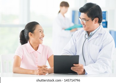 Image Of A Smiling Doctor Consulting His Older Patient On The Foreground