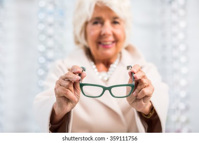 Image of smiling elderly woman trying on fashionable eyeglasses - Powered by Shutterstock