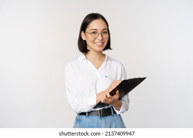 Image of smiling korean office lady, company employee writing down on clipboard, taking notes, standing over white background - Powered by Shutterstock