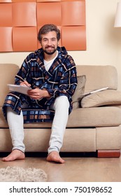 Image Of Smiling Man In Home Dressing Gown With Magazine On Couch