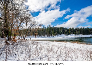 An image of a snow covered lake with a mountain landscape and a partly cloudy sky in the background.   
