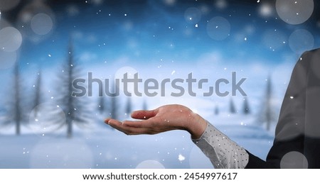 Image of snow falling over hands of caucasian woman and winter landscape. Christmas, winter, tradition and business concept digitally generated image.