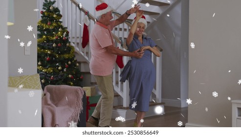 Image of snow falling over senior caucasian couple wearing santa hats and dancing. Christmas, tradition and celebration concept digitally generated image. - Powered by Shutterstock