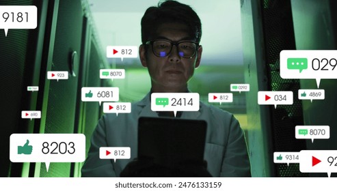 Image of social media icons and numbers over asian male it technician by computer server. Global business, finances, computing and data processing concept digitally generated image. - Powered by Shutterstock